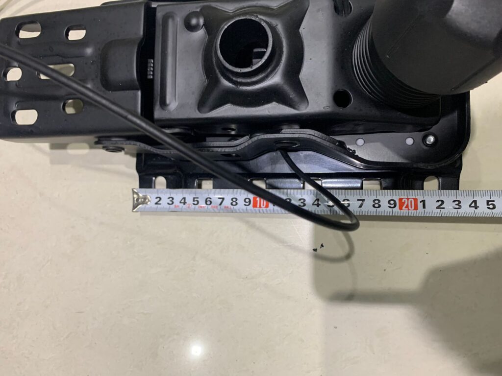 Office chair wire-controlled mechanism being measured with a tape measure to show exact mounting dimensions.
