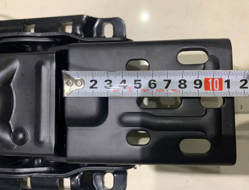 Tape measure aligned to check the longitudinal mounting hole span of a commercial chair mechanism.